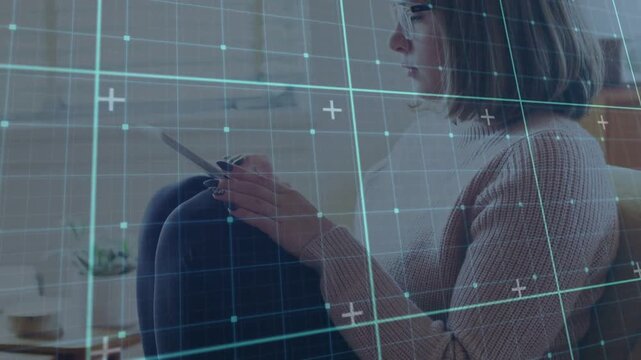 Woman sitting couch tapping tablet, remote working as cyan grid overlay drifting showing glasses