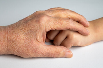 Fototapeta premium Elderly hand holding child hand close up