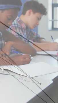 Vertical video: Two students writing, camera pulling back showing desk, nodes tracking pens school