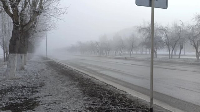 Cars drive along the road during heavy fog in winter. Poor visibility on the road, closure of highways due to weather conditions