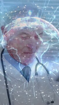 Vertical video: Senior doctor reviewing tablet for notes while holo globe shifting over stethoscope