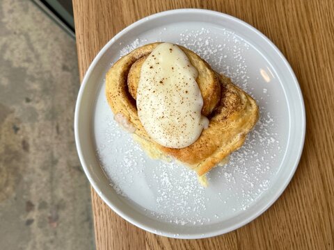 Delicious cinnamon bun with creamy frosting, bite taken, showing fluffy interior texture.