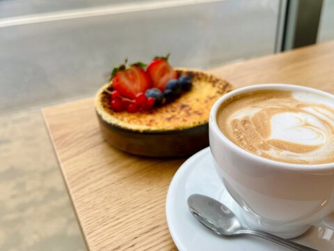 Delicious cr&egrave;me br&ucirc;l&eacute;e with golden caramel crust and berry garnish, creamy texture visible, stylish dessert on wooden background.