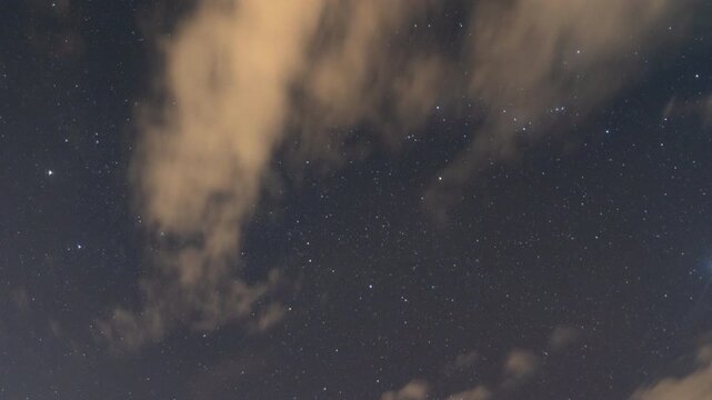 A celestial canvas of stars shimmer through the ethereal veil of clouds, evoking a sense of wonder and the vastness of space. 