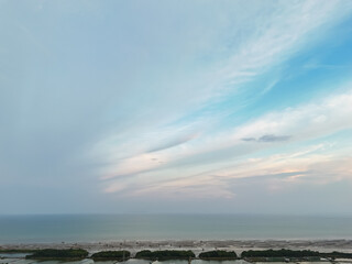 Obraz premium Aerial coastal horizon with soft pastel sky above calm sea and shoreline vegetation