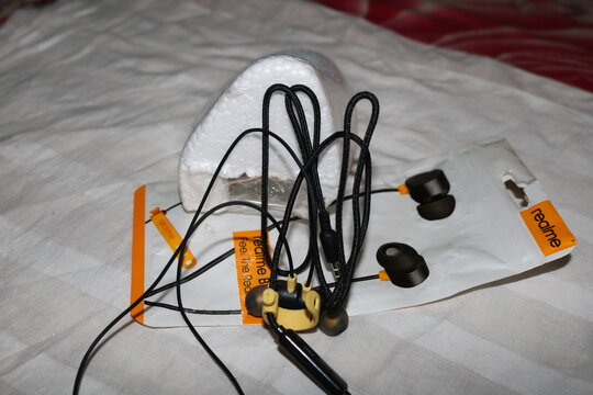 Realme wireless earbuds with charging cable and packaging on a bed