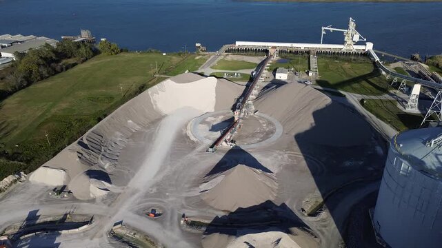 Portside aggregate transfer at industrial corridor along Virginia Ave by Cooper River, Charleston Naval Complex active conveyors feeding dock infrastructure. Fine-grade gravel, steel trusses, SC