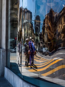 Distorted reflections of buildings and people on glass windows
