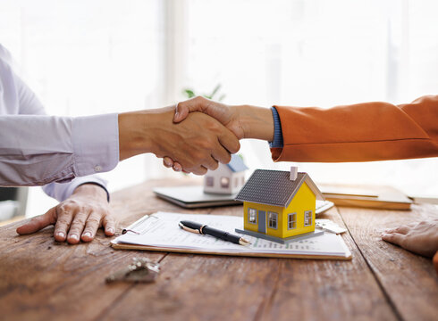 Handshake Real estate brokerage agent Deliver a sample of a model house to the customer, mortgage loan agreement Making lease and buy and sell house And contract home insurance mortgage loan concept