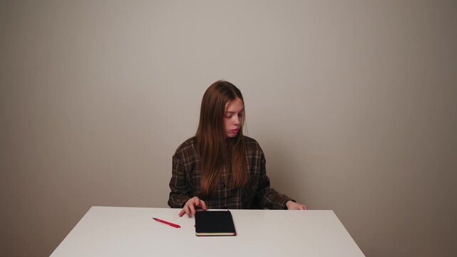 Woman puts smartphone aside and focuses on notebook and work.