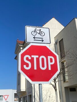 Stoppschild mit Zusatzschild f&uuml;r Fahrr&auml;der im Wohngebiet, Verkehrsschild im Stadtverkehr unter blauem Himmel, Sicherheit im Stra&szlig;enverkehr mit Copyspace
