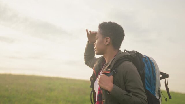 Adventurer in field embracing dawn sunlight, Discovering vast landscapes during morning hike with resolve