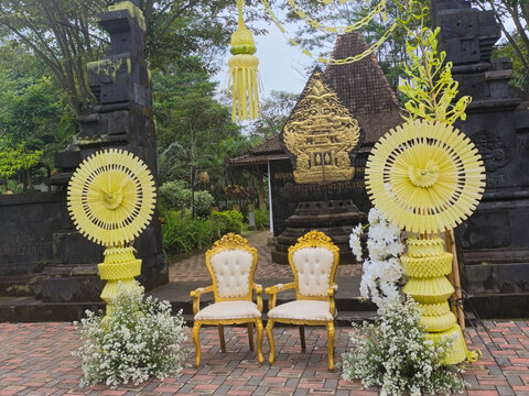 Elegant Javanese Wedding Stage with Golden Chairs, Traditional Gate, Floral Decor and Cultural Ceremony Setup in Outdoor Heritage Temple Courtyard