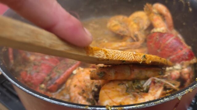 Bogavante o langosta con gambas cocinado al fuego removiendo con cuchara de madera
