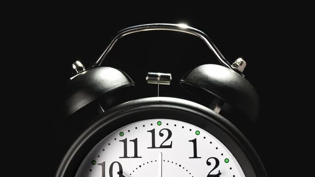 Vintage alarm clock. Clock face on black background. Time lapse. Time running fast. Analog clock. Table clock show running time. Close up in 4K, UHD