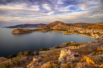 Naklejka premium Lemnos Myrina town, a coastal settlement on a greek island, enjoying a peaceful golden hour light over its harbor bay