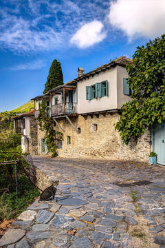 Thasos island, North Greece, Megalos Prinos, Kazaviti. Traditional stone houses and a cat relaxing on a historic cobblestone street.