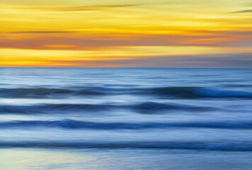 Fototapeta premium Long exposure photography panning of ocean waves breaking at sunset.
