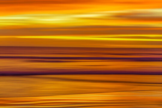 Long exposure photography panning of ocean waves breaking at sunset.