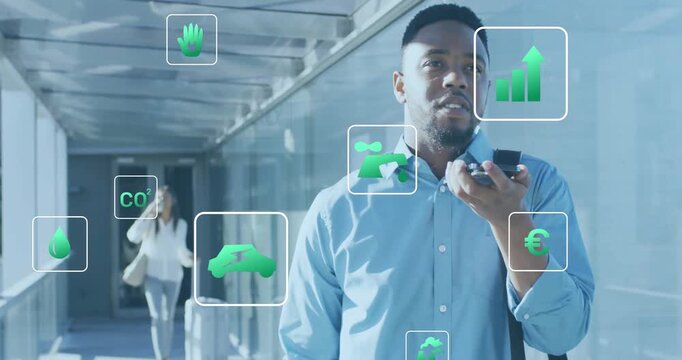 Businessman speaking into phone in airport activating floating eco icons and monitoring metrics