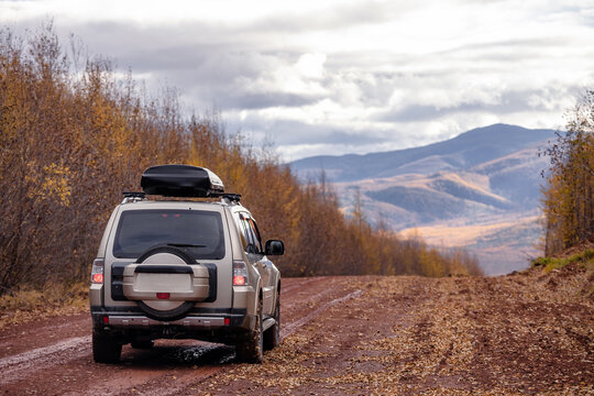 SUV on scenic autumn road in mountains