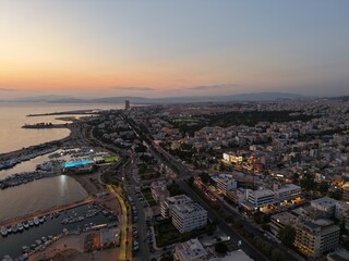 Fototapeta premium Golden sunset over a tranquil sea with yachts and sailboats near a coastal city harbor, in Greece