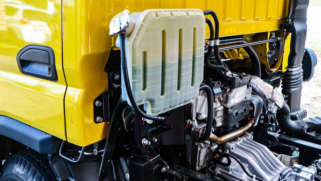 Detailed view of an industrial vehicle's engine compartment, prominently featuring the translucent coolant fluid reservoir and intricate mechanical components