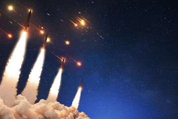 Naklejka premium dramatic night scene depicting a strategic ballistic missile barrage launch under a clear starry sky, with multiple rockets ascending simultaneously, tracer trails filling the sky. War