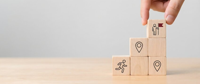 Human hand is carefully placing a wooden block labeled "training" on top of a pyramid made of blocks signifying workshop, leadership, learning, performance, and collaboration.