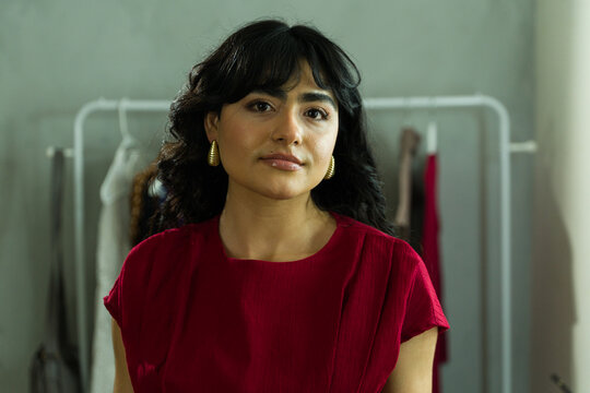 Model posing in red dress, getting ready with professional makeup and jewelry backstage for fashion event