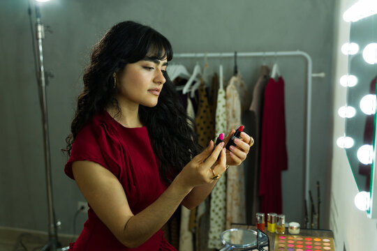 Young woman choosing lipstick shades for makeup getting ready backstage in a dressing room