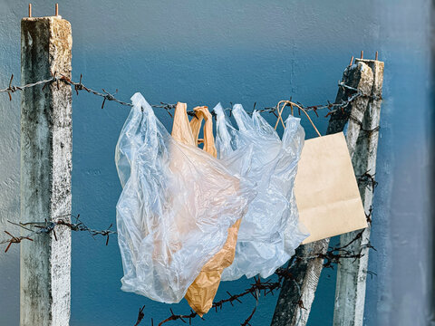 Plastic bag hanging on barbwire fence with paper bag.prepare for reuse.