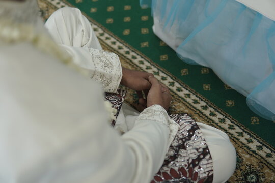 Groom sitting on green carpet during a traditional Indonesian wedding ceremony. Cultural ritual.