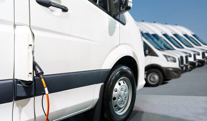 Close up of electric delivery van with connected charging cable © scharfsinn86