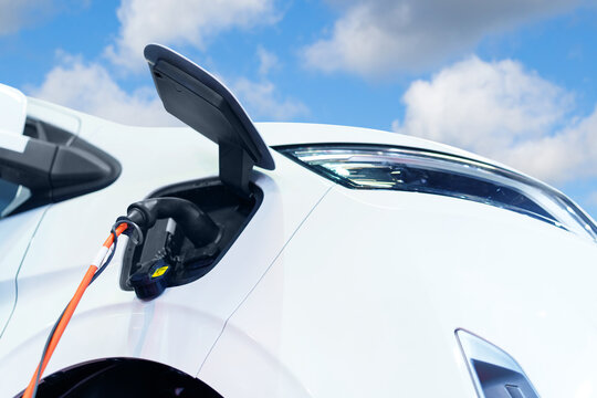 Close up of electric delivery van with connected charging cable