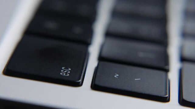 Close view of a finger pressing the Esc key on a laptop keyboard during computer use highlighting the command control area. User interaction, computer workflow.
