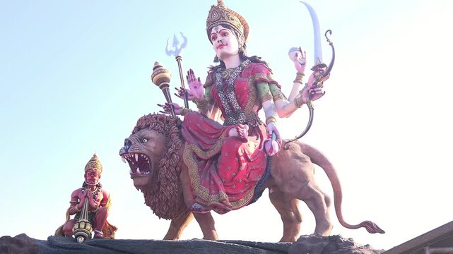Big Goddess Durga statue at sunset in Chaar Dham Temple in Vrindavan, Uttar Pradesh India. Dramatic spiritual scene, golden sky, temple ambiance, ideal for religion, culture, and festival themes.