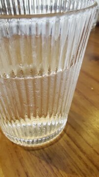 Close-up of half full glass of water on wooden table. Ideal for mindset, lifestyle, and conceptual storytelling visuals.