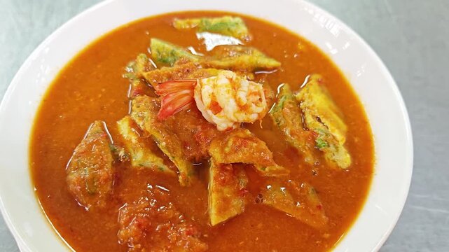 Close up of Kaeng Som Cha-om Kung, Thai sour curry with shrimp and fried acacia omelet.