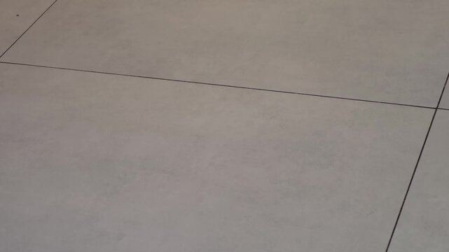 Smooth, light-colored floor tiles with subtle texture and visible grout lines, showcasing a clean and modern interior space in a contemporary setting