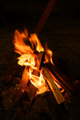 Bright campfire burning with wood logs and stones at night in an outdoor camping area. Concept of adventure, warmth, relaxation, nature travel, and cozy lifestyle.