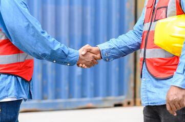 Close up to African African american engineer handshake together at container cargo yard in successful. success in logistics business import export industry.