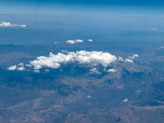 Fototapeta premium Aerial view of mountain range with scattered clouds under clear summer sky in central Greece