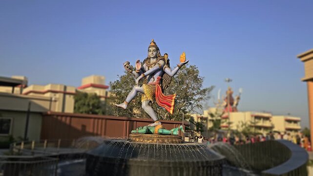 Statue of Lord Shiva in Nataraja Tandava dance pose at Char Dham Temple in Vrindavan, India. The scene represents cosmic creation, destruction, and divine energy in Hinduism. Surrounded by a fountain
