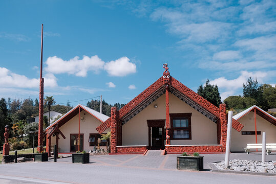 Waitangi Treaty Grounds, New Zealand: The Te Atamira Wharenui featuring traditional Māori wood carvings and Whakairo architecture under a bright sky.