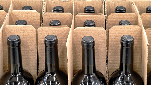 Rows of dark glass wine bottles in corrugated cardboard packaging.