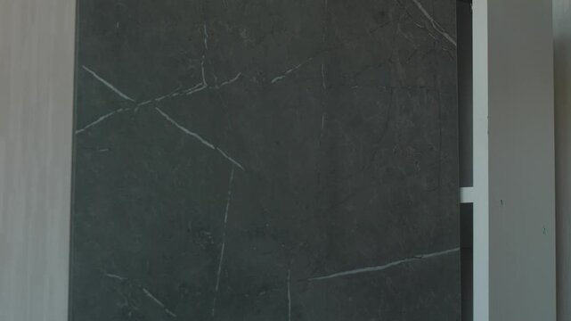 Checking the operation of the kitchen cabinet door after installation. The master closes the gray facade of the kitchen module during furniture assembly