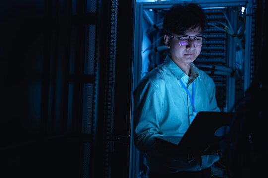 Computer engineer is setting up network in server room,Systems Maintenance Technician,Male engineer working in server room at modern data center