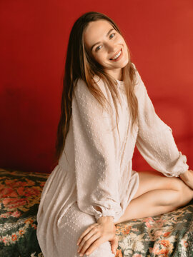 Smiling young woman on red background, beauty boudoir concept