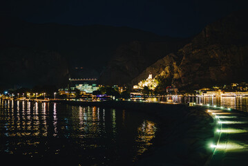 Obraz premium Night view of Omis town and illuminated Mirabella fortress from stone pier.